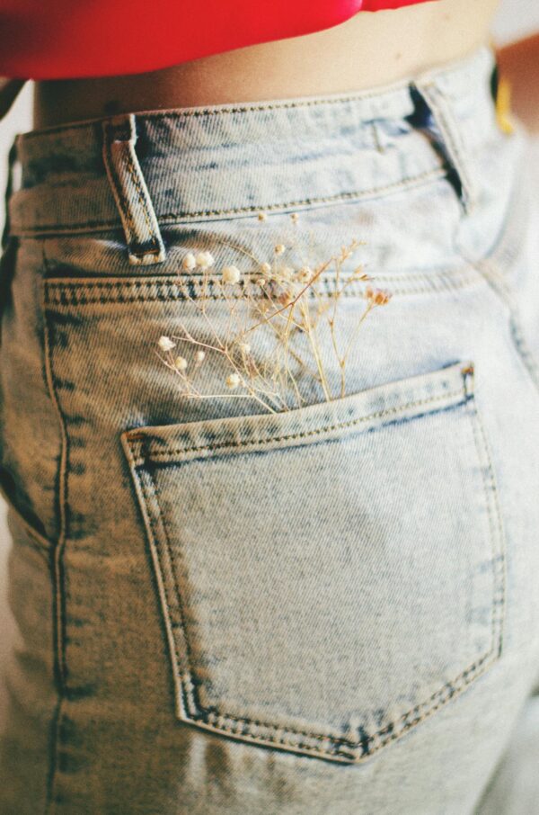 Close-up of denim jeans with delicate white flowers in back pocket, showcasing a stylish look.