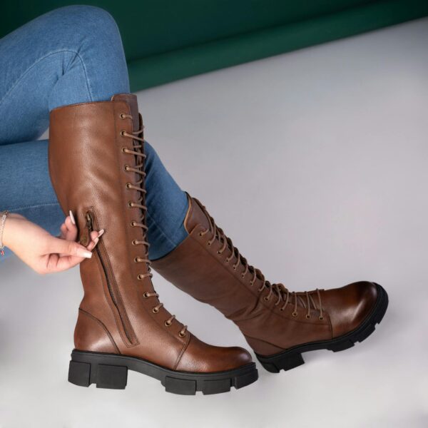 Close-up of fashionable brown leather boots paired with blue jeans for a modern look.